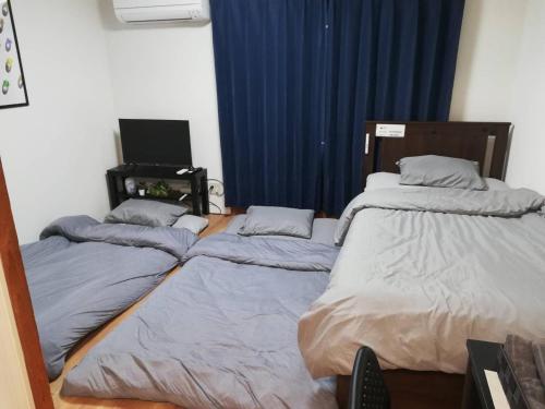 two beds sitting next to each other in a room at お宿あびこシルバーハイツ in Osaka