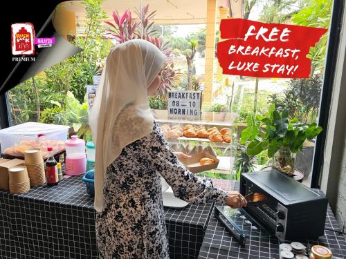 a woman standing in front of a counter cooking food at Rucksack Inn Premium Melaka in Melaka