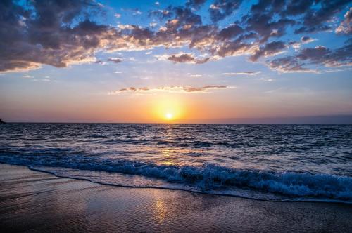 a sunset on the beach with the ocean at Sunset at 30 Nivica Luxury Apartment in Langebaan