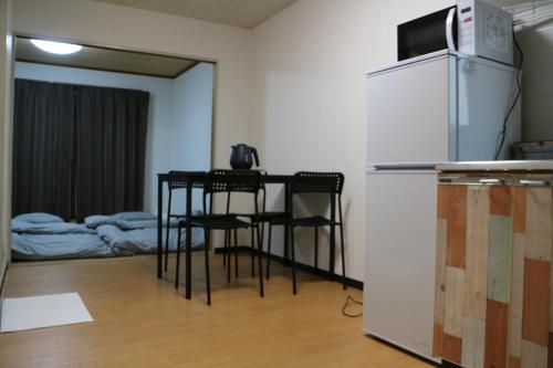 a kitchen with a table with chairs and a refrigerator at お宿あびこシルバーハイツ in Osaka