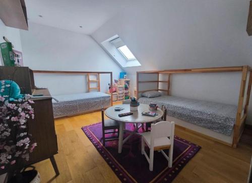 Cette chambre comprend deux lits, une table, une table et des chaises. dans l'établissement La villa du manege, à La Celle-sous-Gouzon