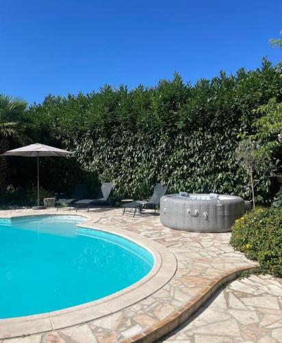 une piscine avec deux chaises et un parasol dans l'établissement La villa du manege, à La Celle-sous-Gouzon
