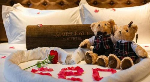 two teddy bears sitting on a bed with roses at James Joyce Coffetel Chengdou Wuqing Wanda Plaza in Chengdu