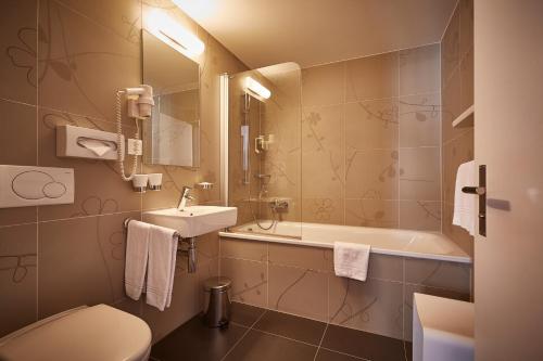 a bathroom with a toilet, sink and mirror at Hotel Landhaus in Gstaad