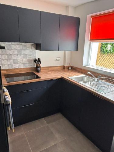 a kitchen with black cabinets and a sink and a window at Corner Cottage in Derby