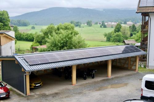 a garage with a solar roof with motorcycles underneath at Gasthof zur Alten Post in Regen