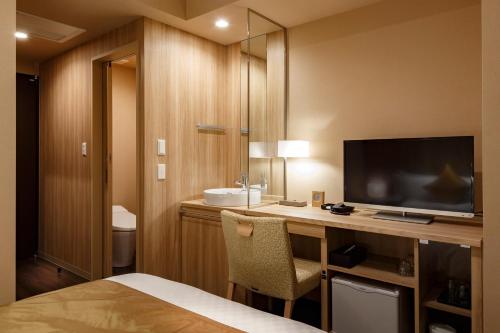 a hotel room with a desk with a tv and a bed at Hotel Vista Sendai in Sendai