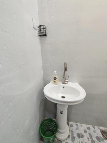 a bathroom with a white sink and a green basket at Nearby fumba joy in Dambani