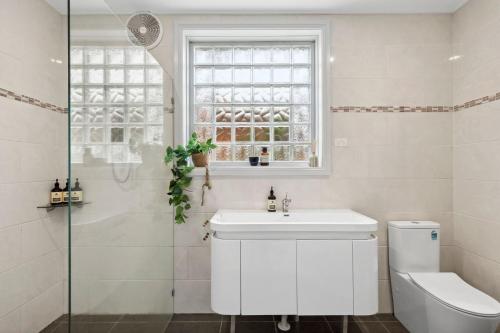 a bathroom with a sink and a toilet and a window at Sapphire Magic 1B in Urunga