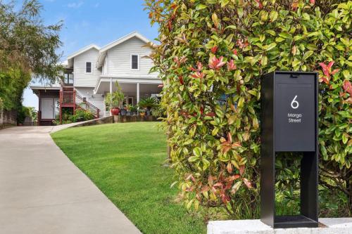 a sign in front of a bush with a house at Sapphire Magic 1B in Urunga