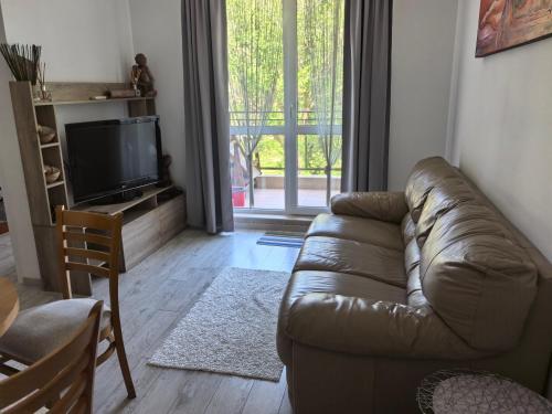 a living room with a leather couch and a television at Апартамент Лятно изкушение in Balchik