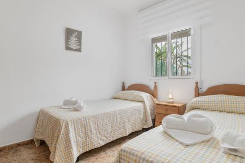 a bedroom with three beds and a window at Villa Manuel y Paca in Conil de la Frontera