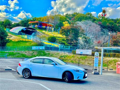 a white car parked in a parking lot with a roller coaster at 犬山モダンルーム in Inuyama