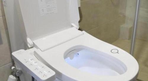 a white toilet in a bathroom with a shower at 7 Days Premium Yancheng Dafeng Zhongjiao Meilu City in Yancheng