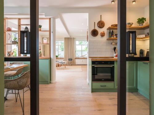 a kitchen with green cabinets and a dining room at NEU Nature Retreat - Traumhafte Wohnung mit privater Sauna - 100m vom Strand in Rerik