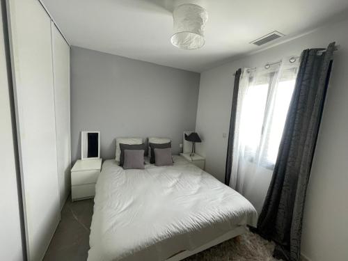 une chambre blanche avec un lit et une fenêtre dans l'établissement Villa cosy 10 min de Montpellier, à Saussan