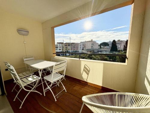 un balcon avec une table et des chaises et une grande fenêtre dans l'établissement STUDIO CABINE CLIMATISE AVEC CHAMBRE ALCÔVE, au Cap d'Agde