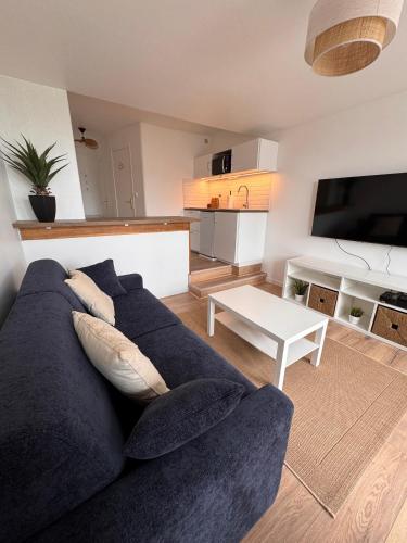 un salon avec un canapé bleu et une table dans l'établissement Studio avec balcon vue mer, à Deauville