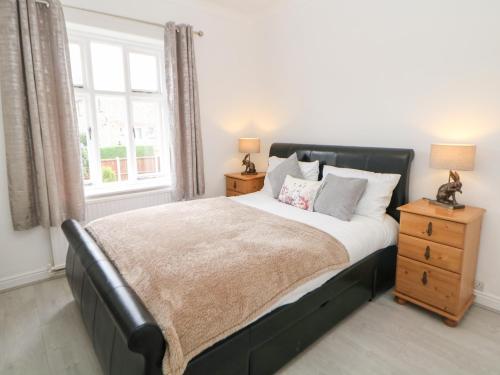 Schlafzimmer mit einem Bett mit einem schwarzen Kopfteil und einem Fenster in der Unterkunft 15 Calton View in Bakewell