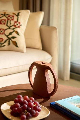 a table with a vase and a plate of grapes at Alkyna Lifestyle Beach Resort - Adults Only in Agios Gordios