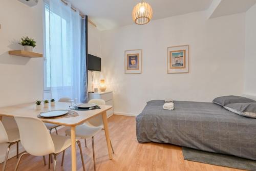 une chambre avec un lit, une table et des chaises dans l'établissement Le Mistral a deux pas du vieux port, à Marseille