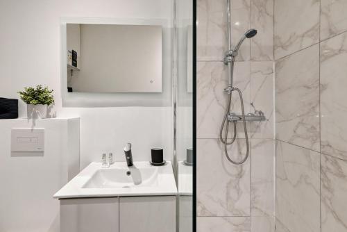 une salle de bain blanche avec une douche et un lavabo dans l'établissement Le Mistral a deux pas du vieux port, à Marseille