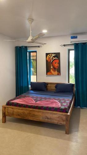 a bed in a room with blue curtains at Sand Beach Boutique in Bwejuu