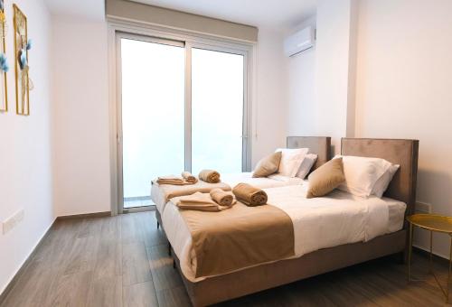 a bedroom with two beds and a large window at Nissinest Luxury Villas in Ayia Napa