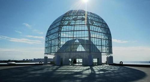 a large glass dome building with the sun behind it at Hotel IL FIORE Kasai in Tokyo