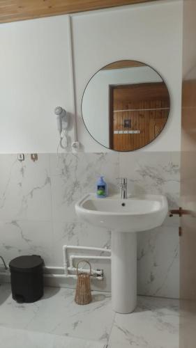 a white bathroom with a sink and a mirror at Casa Marco in Lepşa