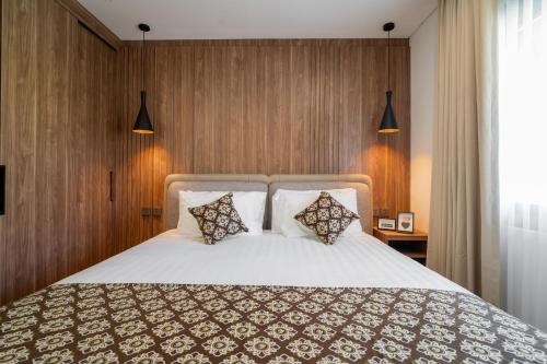 a bedroom with a large white bed with two pillows at Plagoo Holiday Hotel in Nusa Dua
