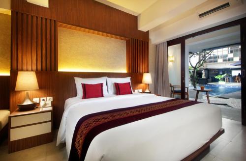 a bedroom with a large white bed with red pillows at Nadi Hotel Legian in Legian