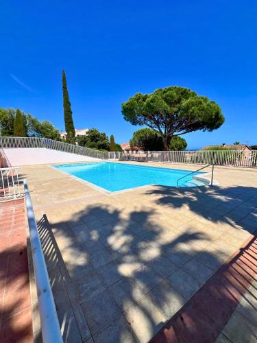 une piscine avec un arbre en arrière-plan dans l'établissement Villa Les Terrasses de Giens, à Hyères