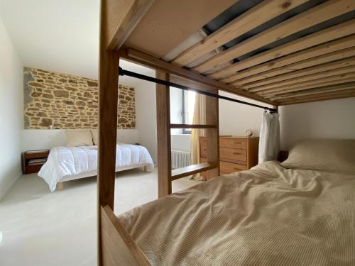a bedroom with two beds and a stone wall at Maison haut de gamme 14 couchages - Baie du Mont Saint Michel in Champeaux