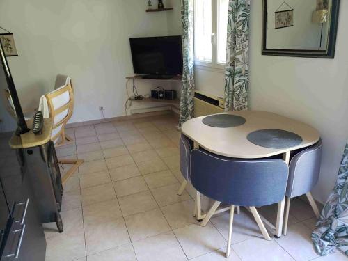 une pièce avec une table, des chaises et une télévision dans l'établissement Charmante petite maison de campagne, à Jouques