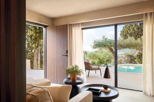 a living room with a view of a pool through a sliding glass door at Alkyna Lifestyle Beach Resort - Adults Only in Agios Gordios