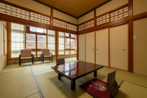 a room with a table and chairs and windows at Fujisan Ryokan in Hanamaki