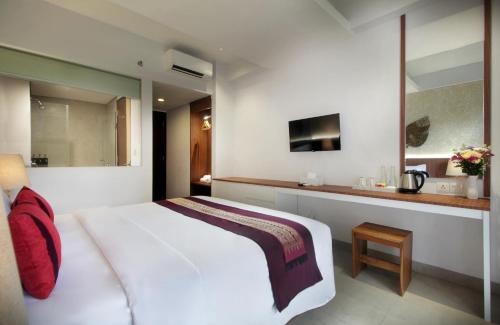 a bedroom with a large white bed and a mirror at Nadi Hotel Legian in Legian