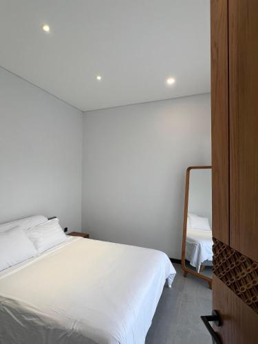 a bedroom with a white bed and a mirror at Villa Mecca in Batu