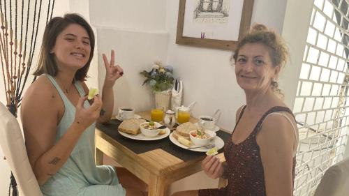 two women sitting at a table with a plate of food at African Angel House B&B in Stone Town