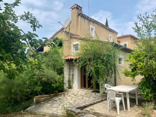 a table and chairs in front of a house at Mas Pinède et Pierre in Saint-Julien-de-Peyrolas