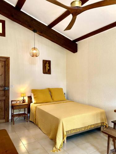 a bedroom with a bed with yellow sheets and a ceiling at Mas Pinède et Pierre in Saint-Julien-de-Peyrolas