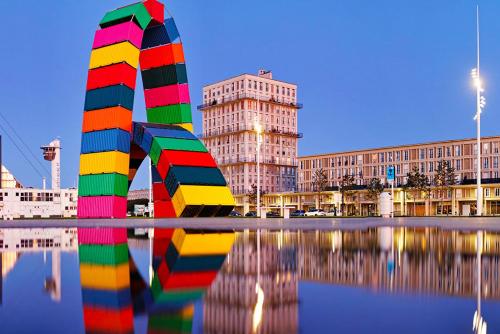 une sculpture colorée dans l'eau devant un bâtiment dans l'établissement Le petit Drapiers 4 Pers a 5 Minutes a pied du petit port et 10 Mins de la plage, au Havre