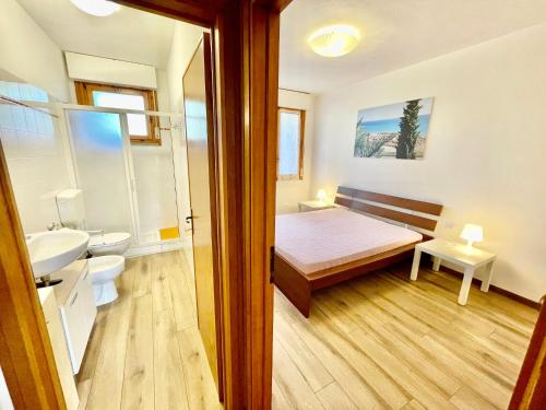 a bedroom with a bed and a bathroom with a sink at Bilocali del Sole in Marina di Bibbona