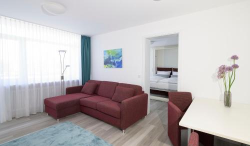 a living room with a red couch and a bedroom at Huber Living in Germering