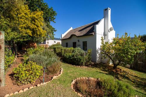 a white house with a garden in front of it at Plum Tree Cottage in McGregor