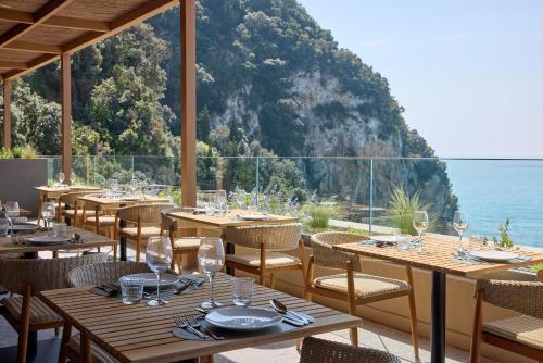 a restaurant with tables and chairs with a view of the ocean at Alkyna Lifestyle Beach Resort - Adults Only in Agios Gordios