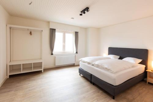 a bedroom with a large bed and a window at Aan de bosrand in Oudsbergen 
