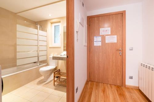 a bathroom with a toilet and a wooden door at Barthe Holidays I Acogedor apartamento en Arinsal 6PAX a pie de pistas I Balcón con vistas y parking I Madness in Arinsal