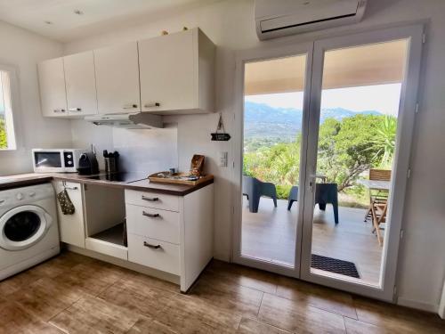 une cuisine avec des placards blancs et une porte coulissante en verre. dans l'établissement Casa Maïtte, à Sotta